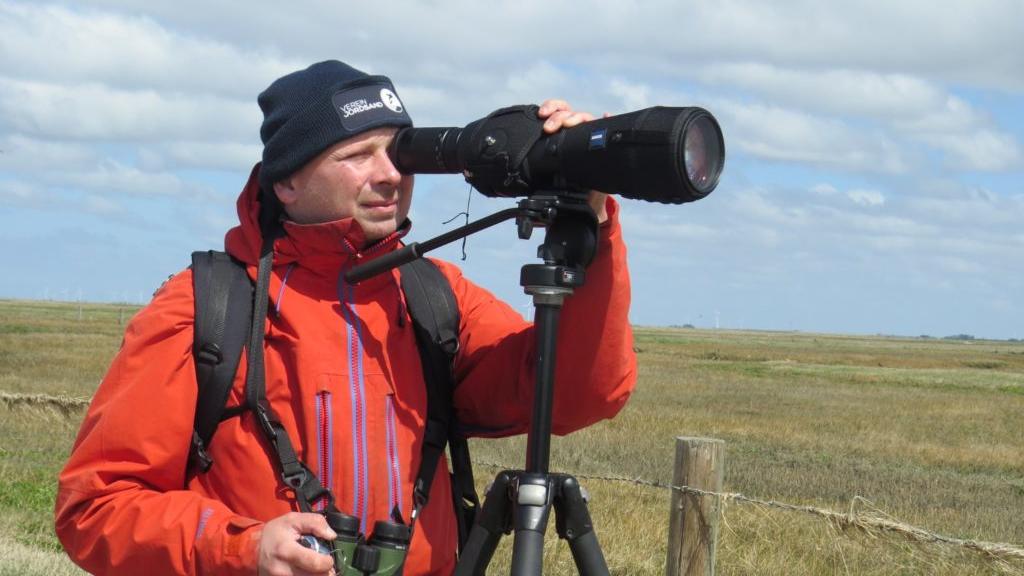 Ornithology warden in red jacket watching birds