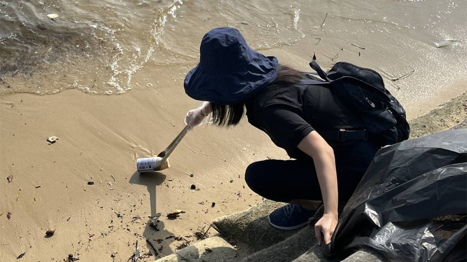 A ZEISS Singapore employee picking up litter at a beach