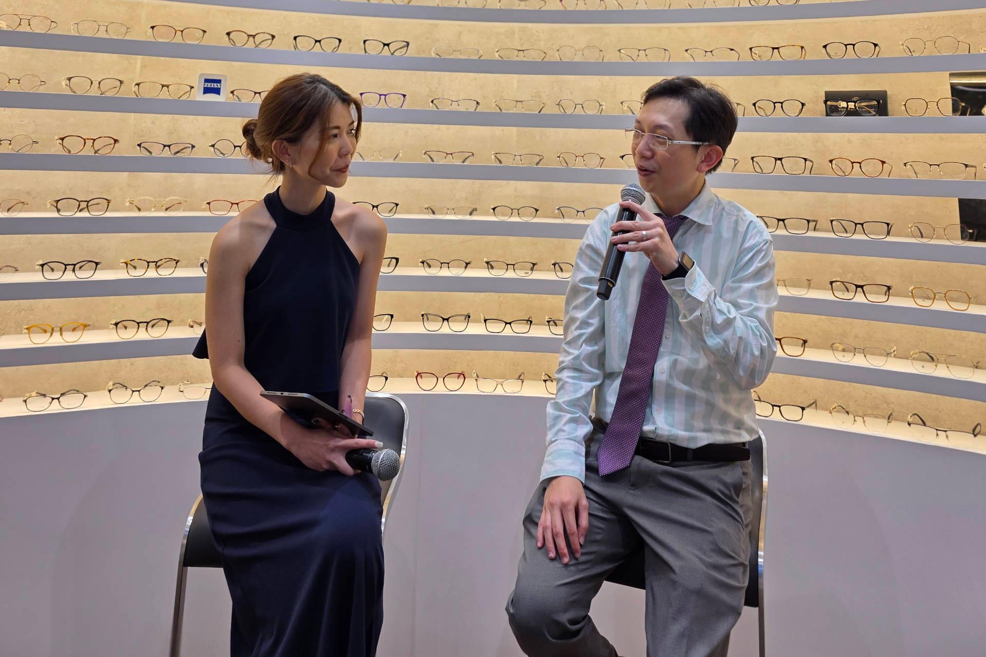 Two people sitting in the back of the Zeiss Vision Center in Singapore are talking to the attendees at the opening ceremony.