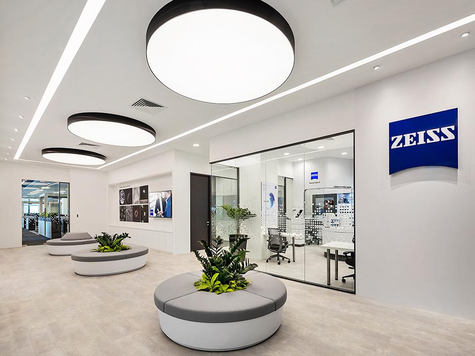 Image of ZEISS Singapore building interior - a large white room with circular seating and green plants