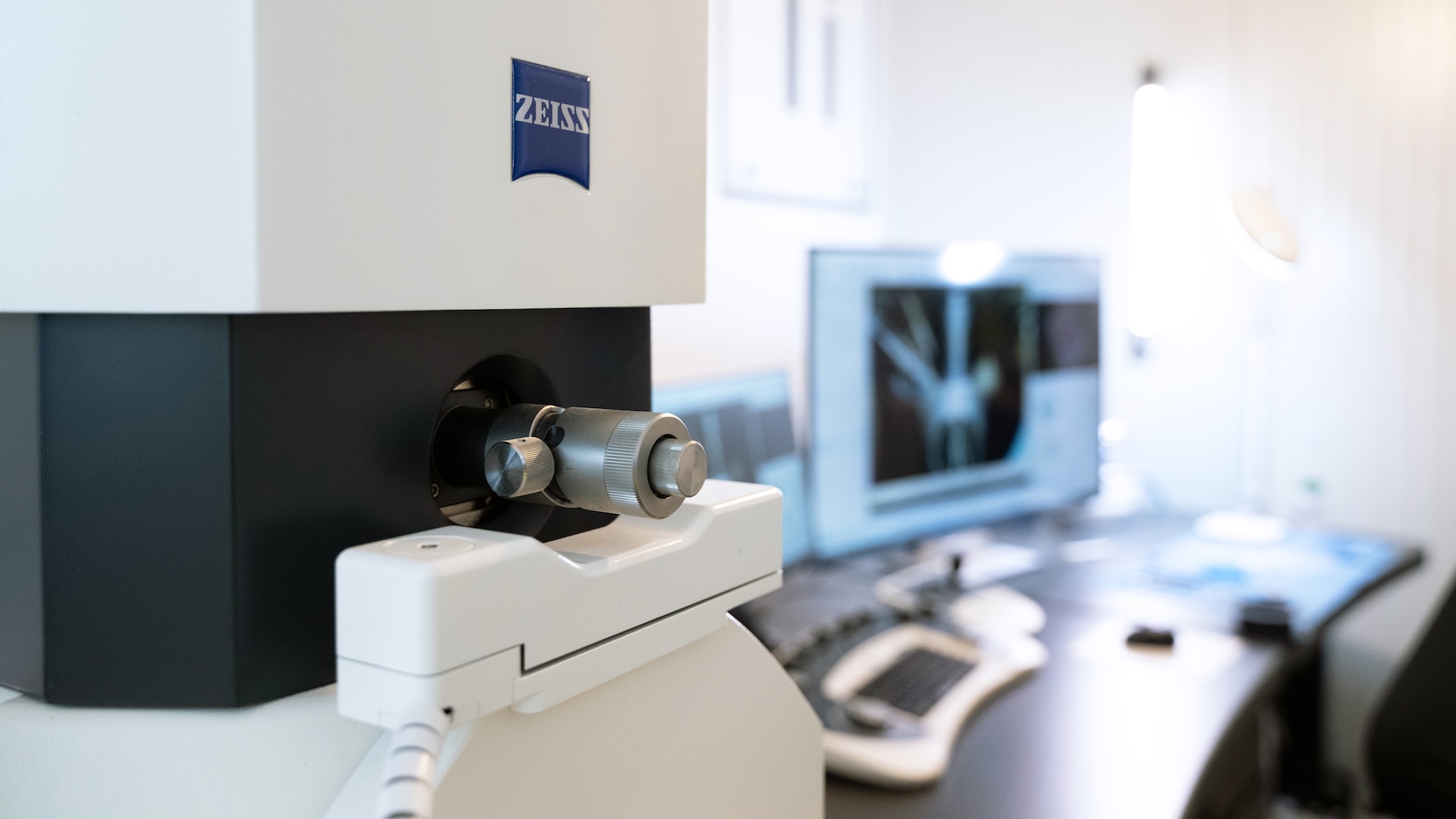 Close-up of a ZEISS EVO in front of a workstation with a computer displaying a scanned image.