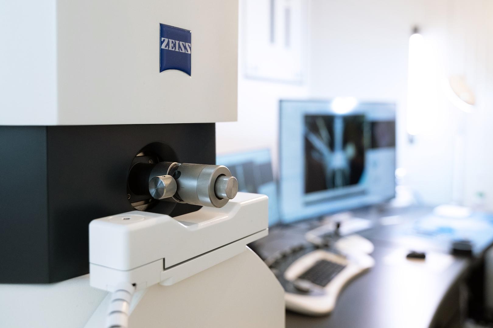 Close-up of a ZEISS EVO in front of a workstation with a computer displaying a scanned image.
