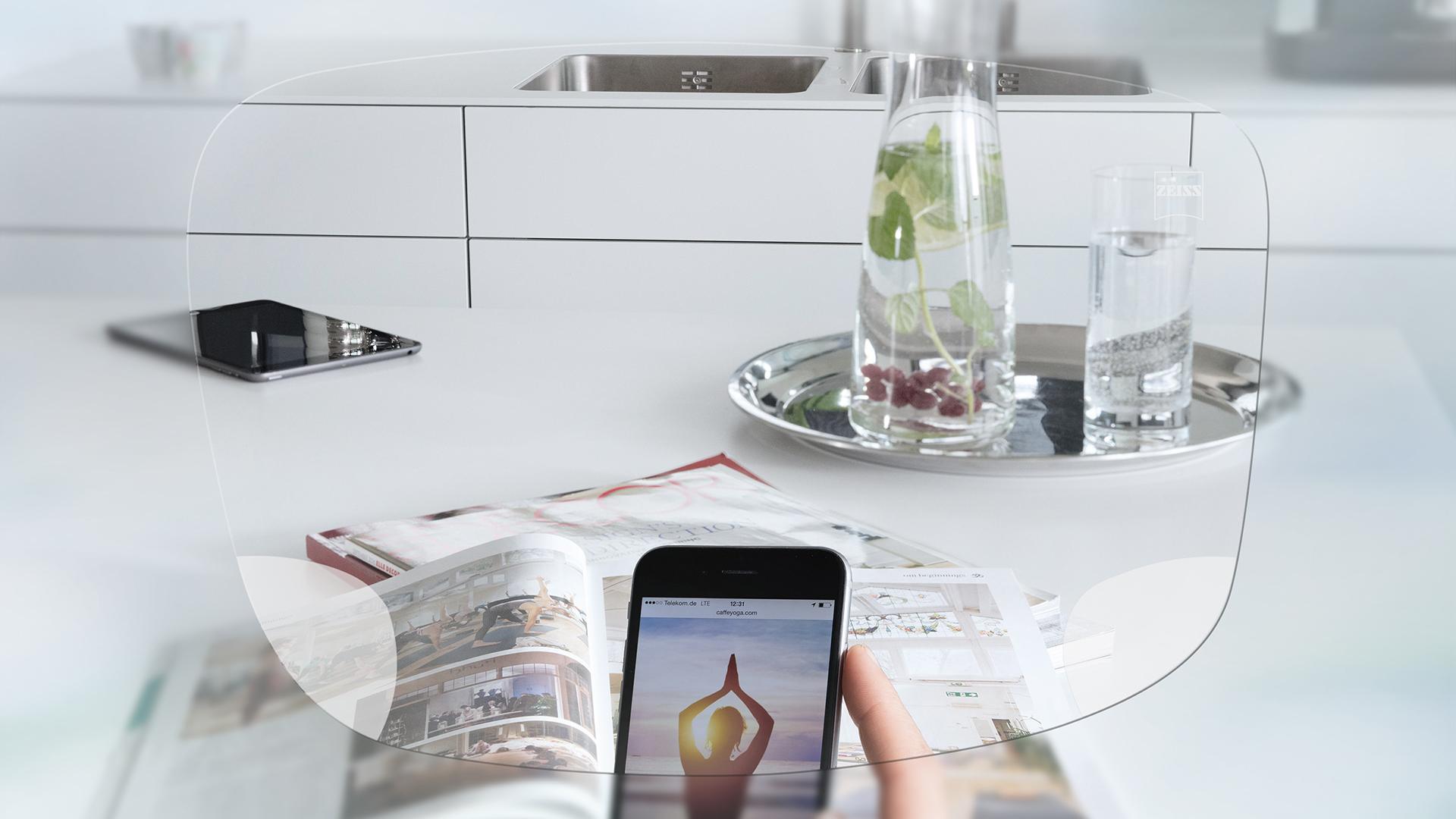 View through ZEISS EnergizeMe Single Vision lens of a smartphone screen and organised kitchen table. 