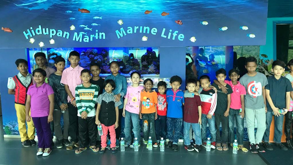 Image of the orphans from Rainbow Home orphanage during the education tour in the Hidupan Marine, Marine life, standing in front of a big aquarium
