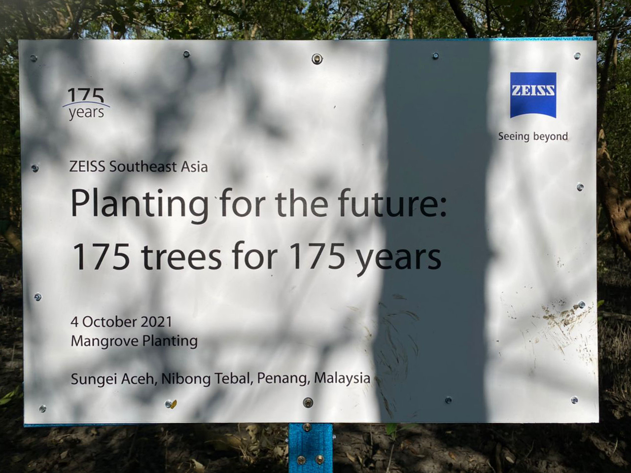 A sign in the field reading ZEISS Southeast Asia - Planting for the future: 175 trees for 175 years