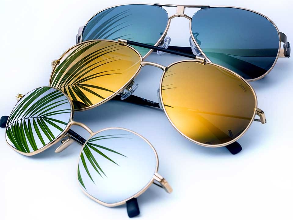 Photograph of three sunglasses with mirror lens coatings in different colours (clear, yellow and blue) 