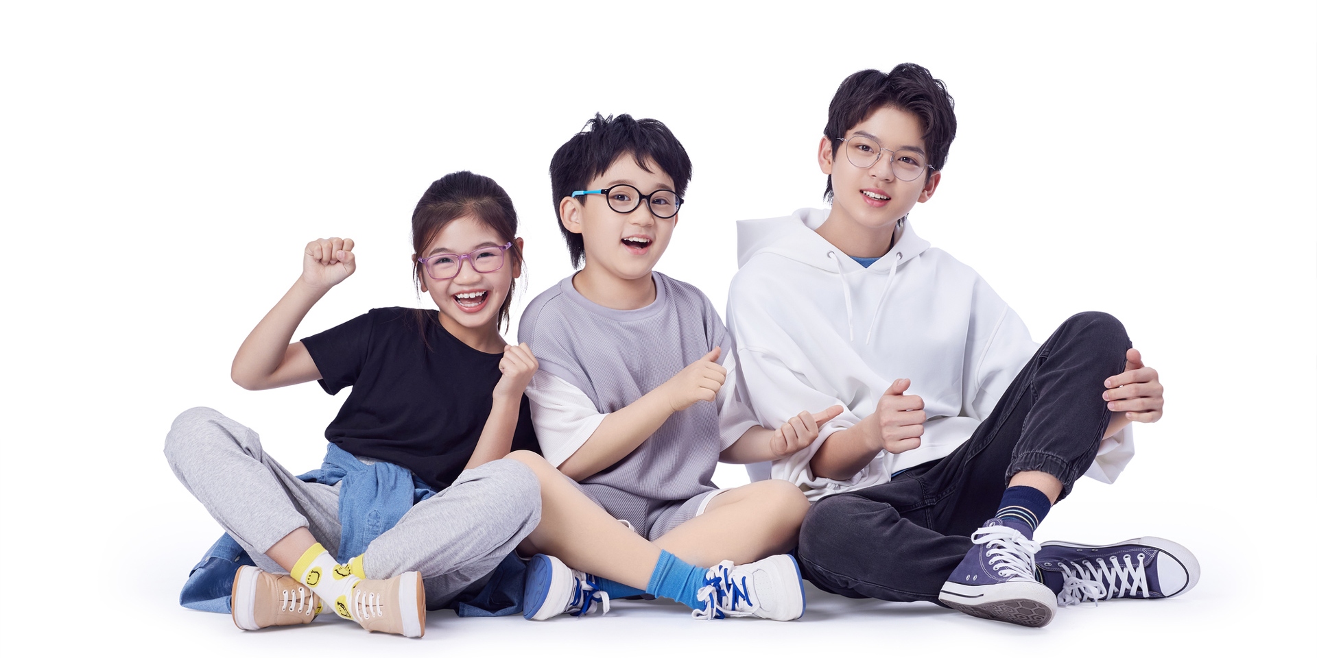 A teenager and two younger children sitting on the floor wearing ZEISS Myopia lenses